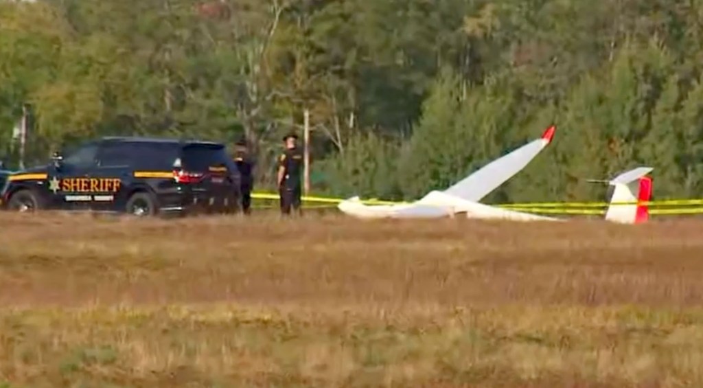 Sheriff's vehicle and gliders on a grassy field after a collision.