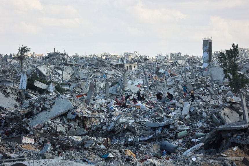 Palestinians search the rubble of buildings amid Israeli bombardment in Khan Younis, in the southern Gaza Strip, on October 12, 2025.