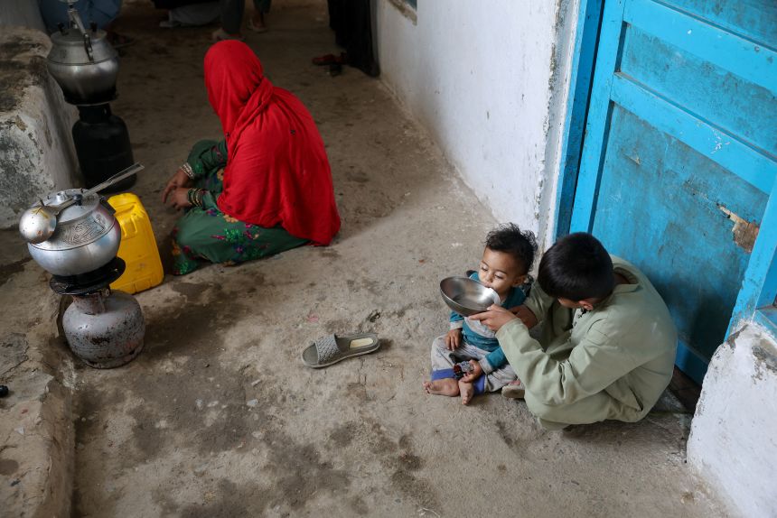 Eight-year-old Sanaullah gives water to his younger brother while their mother is preparing lunch at their home, in Kabul, Afghanistan, August 28, 2025.