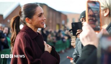 The Duchess of Sussex clutches her hands and smiles warmly as she greets fans waiting for her and Harry in Nottingham