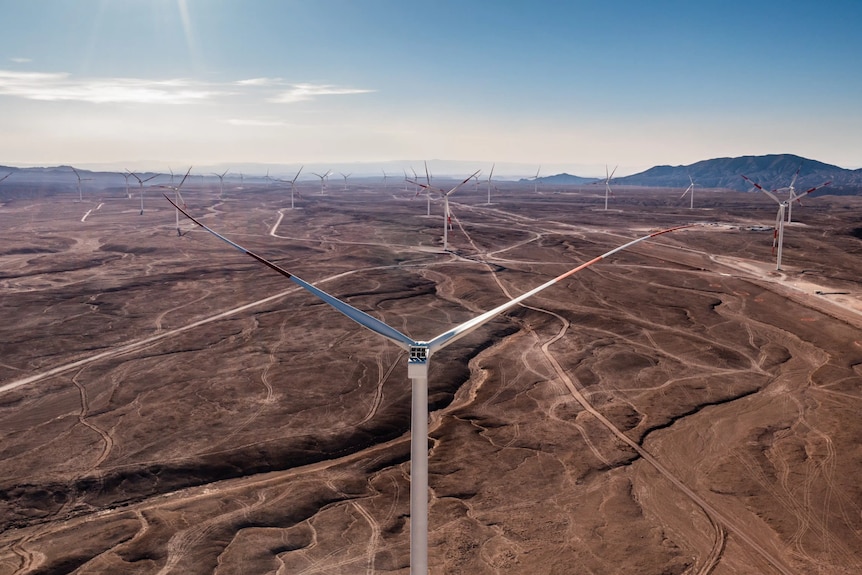 A drone photo of a barren brown landscape with large wind turbines