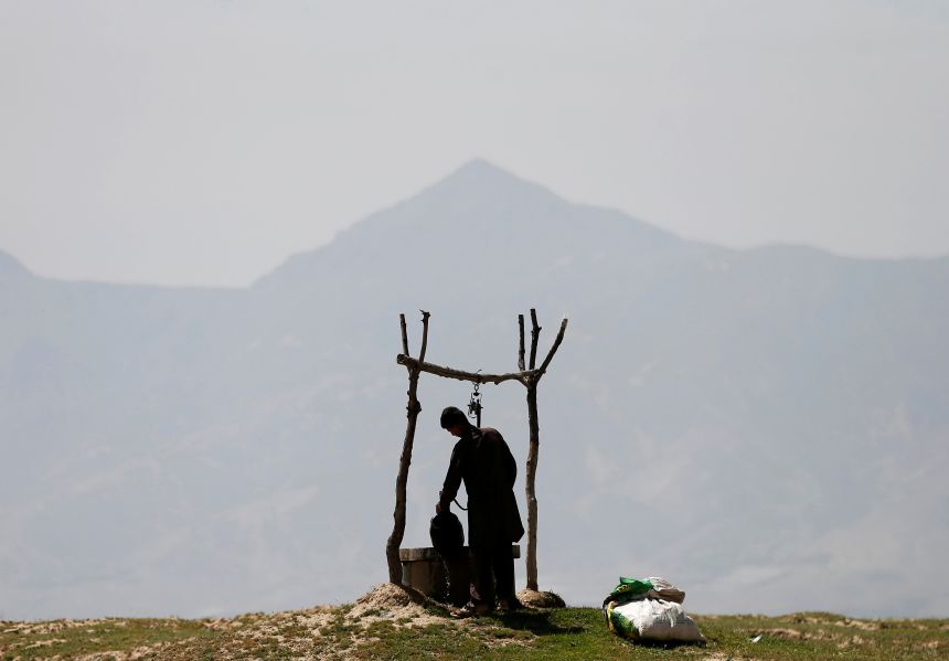 An Afghan boy collects water from a well on the outskirts of Kabul, Afghanistan, on May 12, 2020.