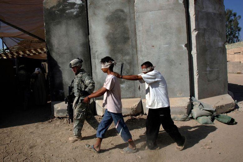 A US soldier leads a pair of Iraqi men after they were detained during a foot patrol along the Tigris River south of Baghdad in September 2007.