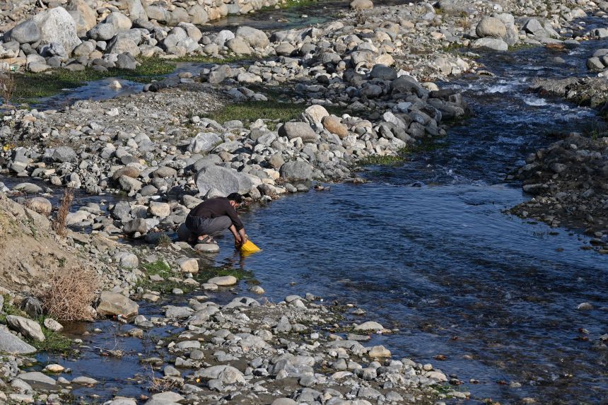 An Afghan man fills water in a can from a river in the Istalif village of northwest Kabul on November 22, 2023.