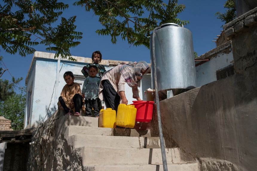A woman collects water from a water tanker on a hillside in Kabul.