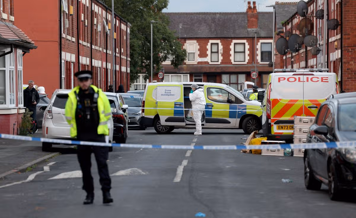 Police and forensic officers at the scene of a murder on Crondall street in Moss Side
