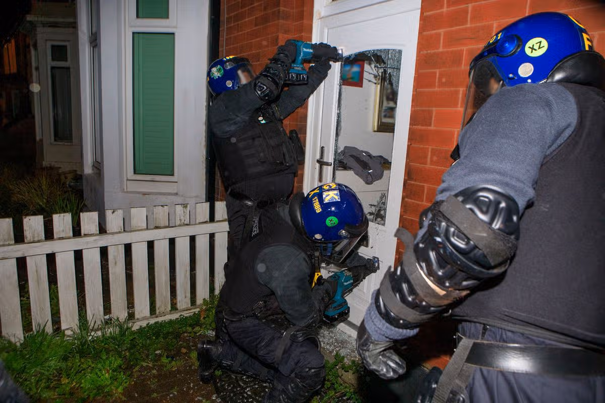 Police make their way into a house during a raid
