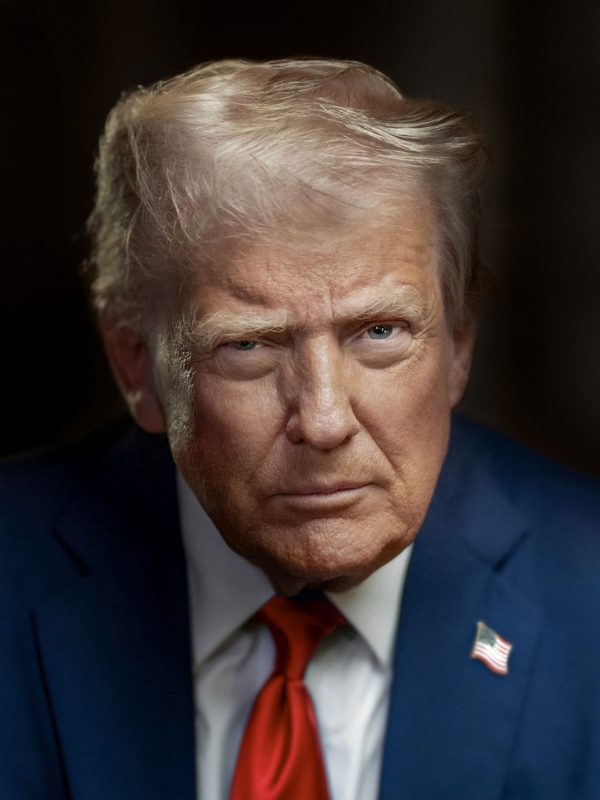 official studio portrait of a man in suit, US flag backdrop
