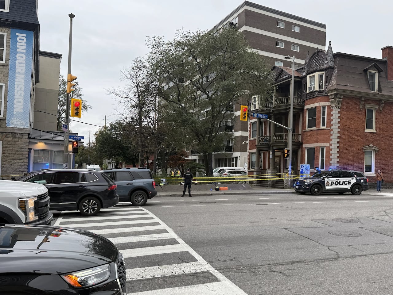 A police officer stands near a section of downtown sidewalk taped off in yellow.