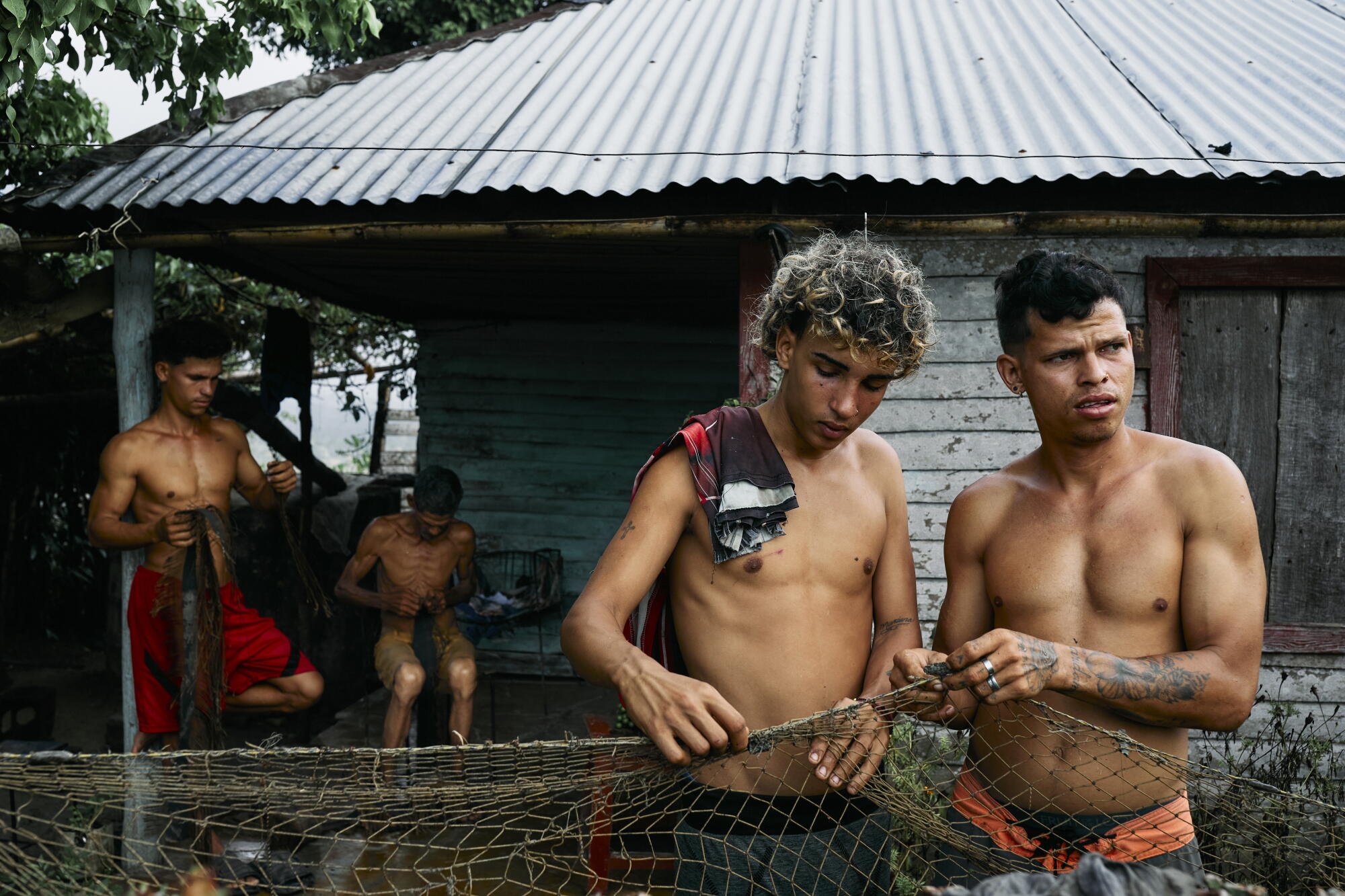 Four men fix a fishing net to catch food for the day in Baracoa.