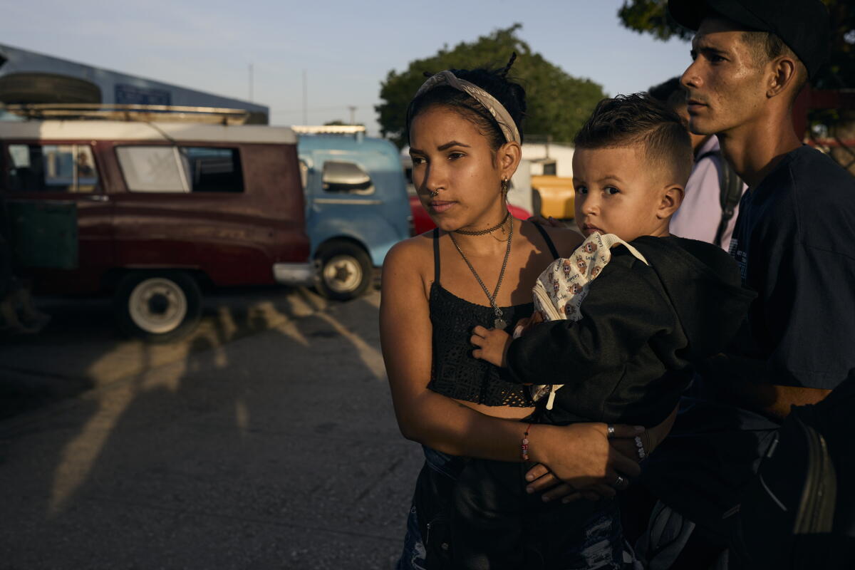 Elianet Cabrera Ramírez, 21, waits for a collective taxi in  Holguín, with her son, Alan Manuel, 2, and Marlon Antonio Jara, 23.