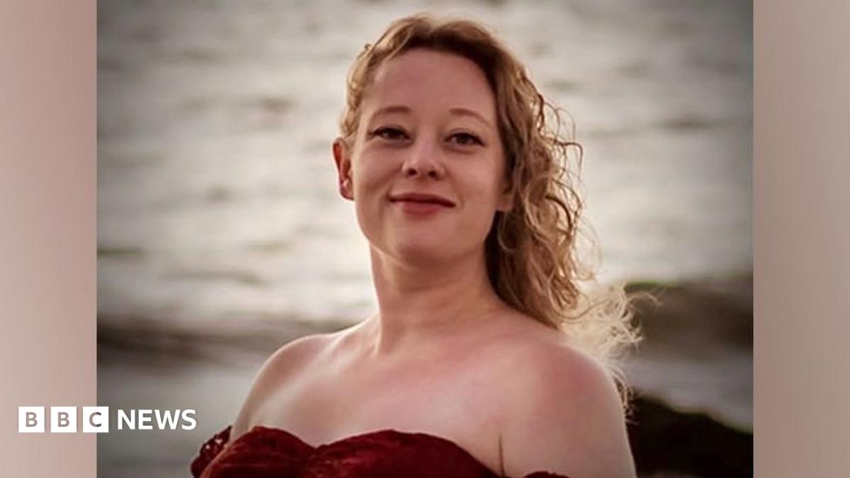 A man speaking into a microphone and holding a flag