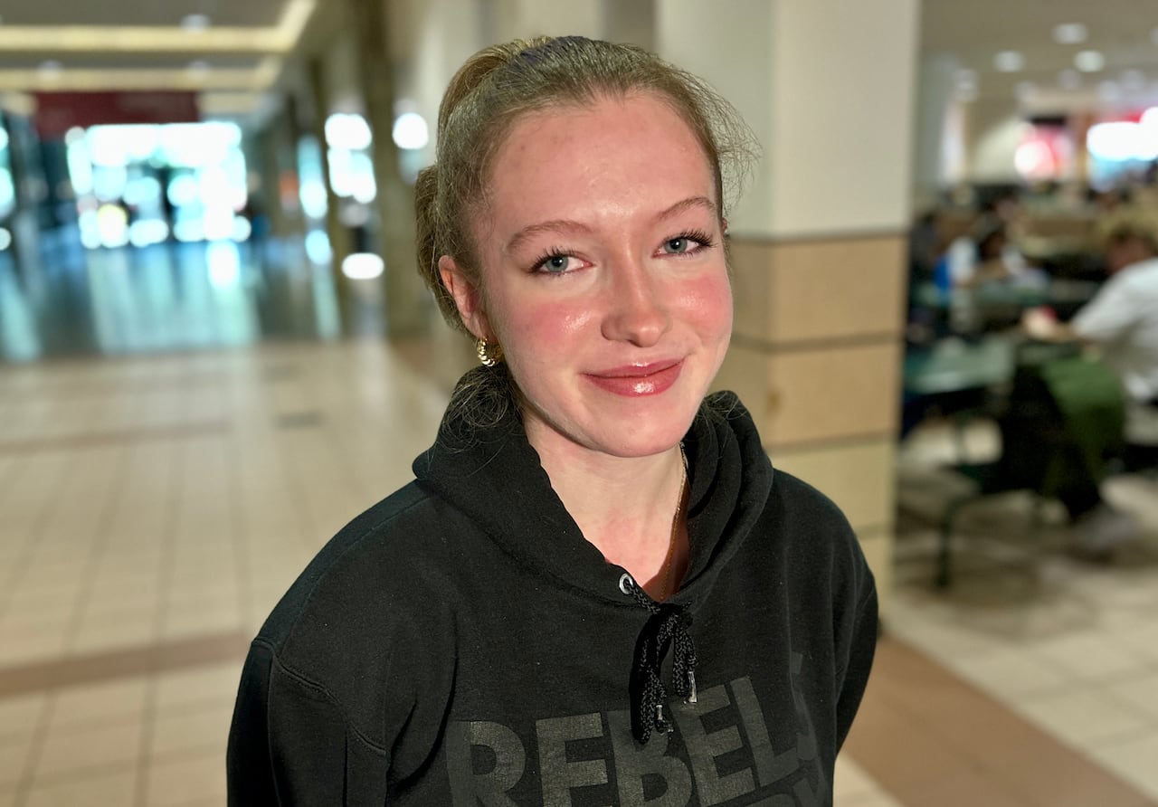A young woman in a black hoodie smiles at the camera.