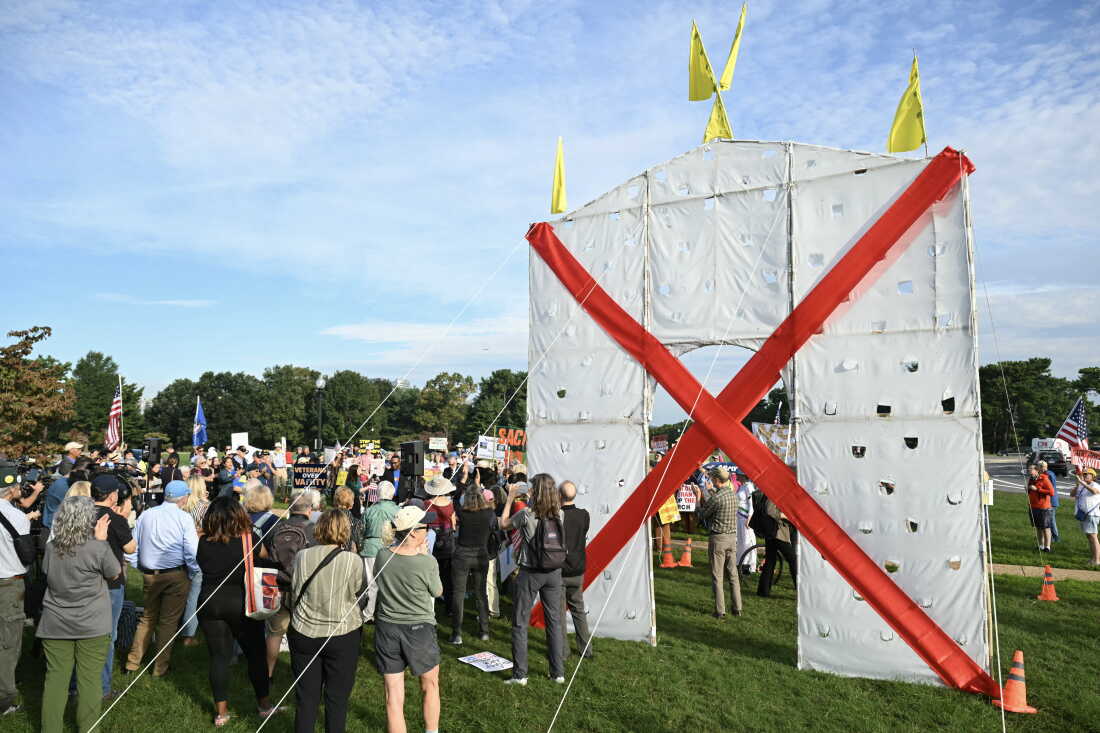 Protesters stand in Memorial Circle near a mockup of Trump's arch, which they say would be 32 times taller.