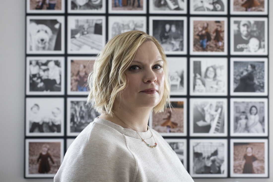 Marlatt stands in front of a grid of framed family photos.
