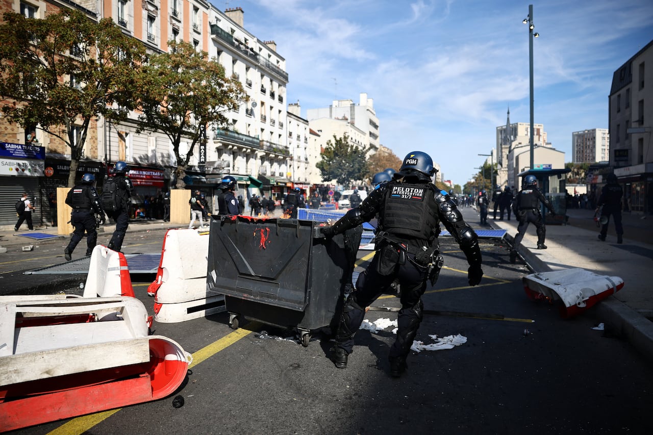A city street scene is shown, with police officers and barricades.