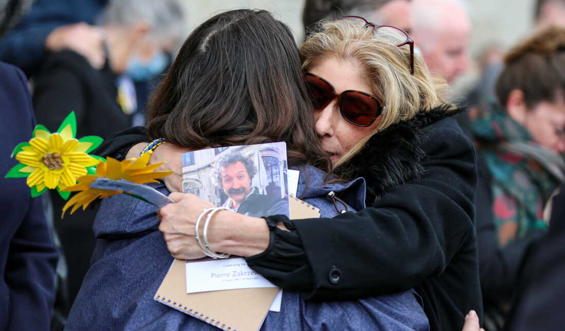 Michelle Ross-Stanton, on the right side of the frame, hugs a woman outside the Church of Our Lady of Perpetual Succour in Dublin on March 29, 2022. Ross-Stanton is wearing a black coat and sunglasses.