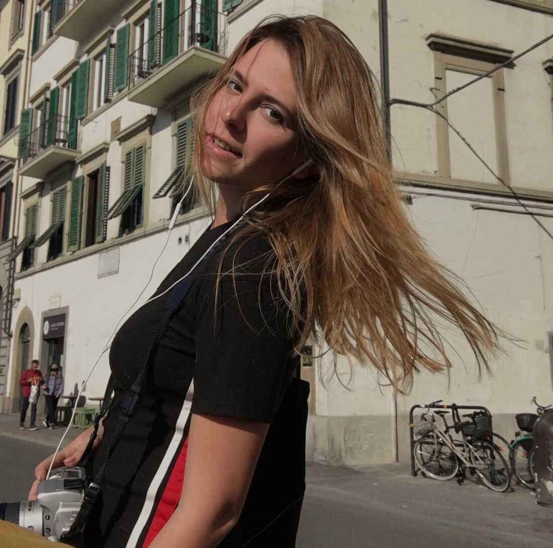 Oleksandra Kuvshynova stands outside a multistory building with green wooden shutters while visiting Italy in 2021.