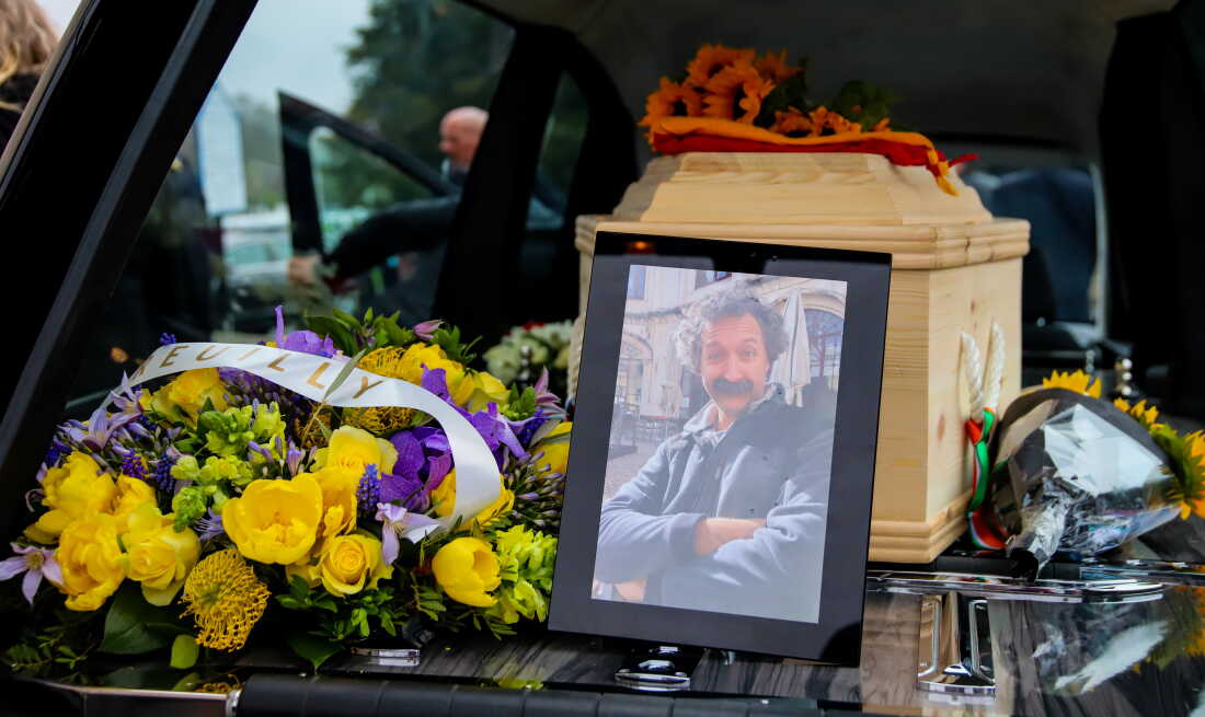 A framed photo of Pierre Zakrzewski is displayed in the hearse following his funeral in Dublin on March 29, 2022. Yellow and purple flowers are next to the photo, on the left side of the frame.