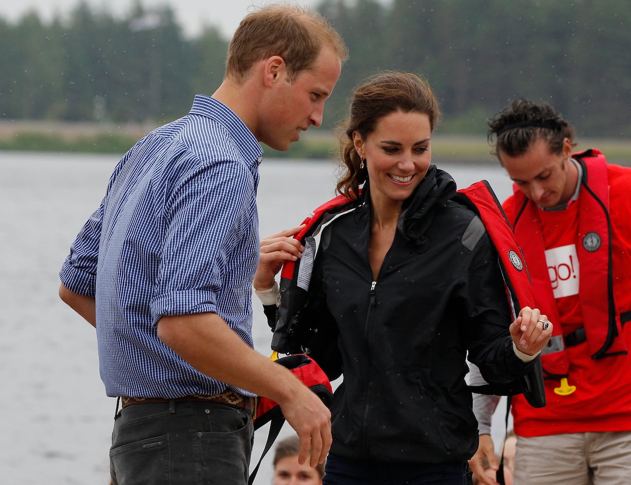 Three people stand on a dock with a body of water behind them.