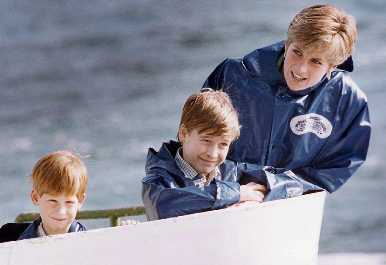 An adult and two children lean against the side of a boat.