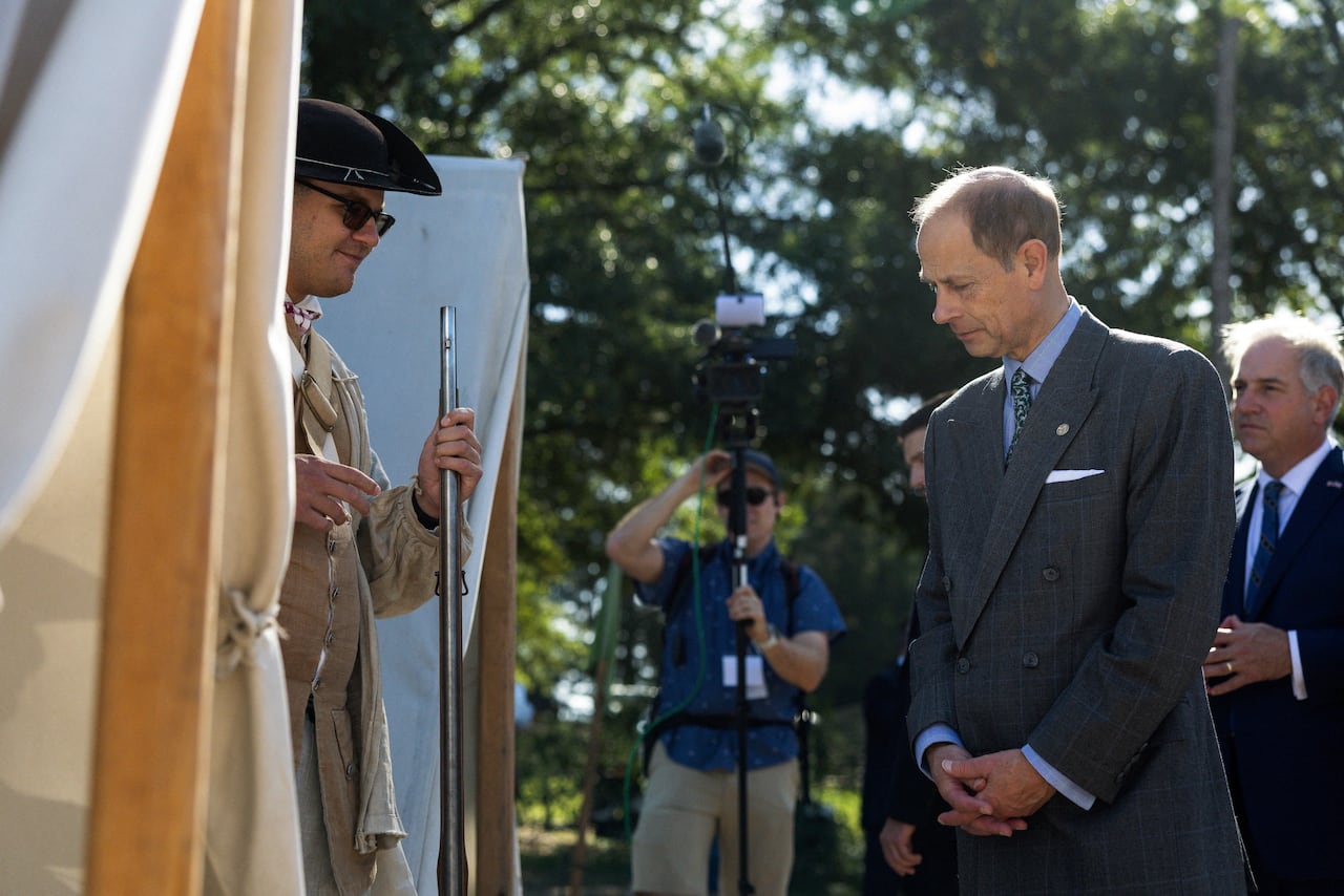 A man in a suit speaks with a man in period dress.