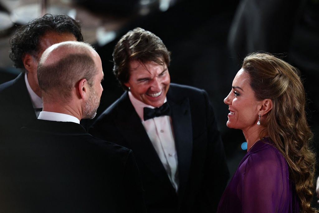 Three people stand and talk with one another.