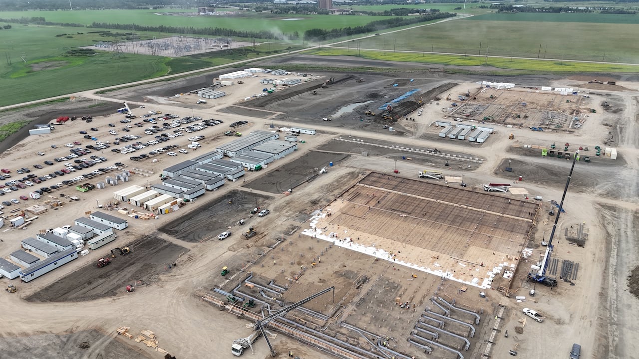 Photos taken from a drone show workers and heavy machinery at a construction site.