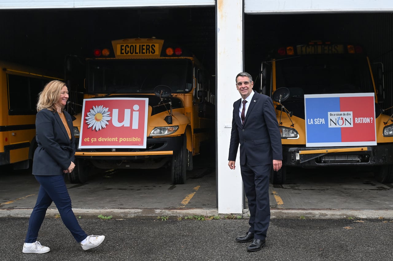 Quebec Conservative Leader Éric Duhaime and local candidate Maïté Blanchette-Vézina in front of two buses with 1995 Yes and No referendum signs, at a campaign wrap up news conference in Quebec City, Friday, Oct. 2, 2026.