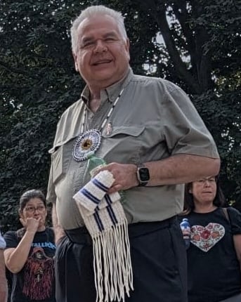 Man hold 2 row wampum belt.