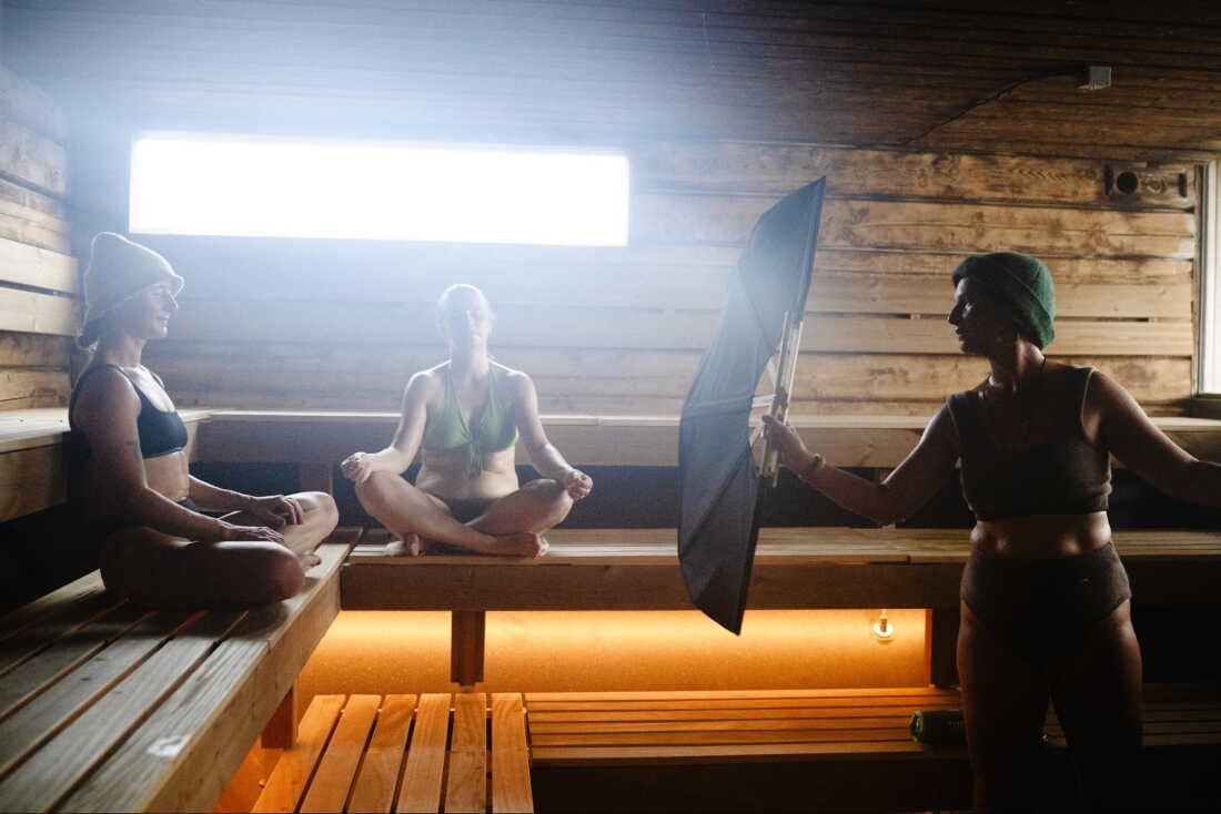Sauna master Hilde Karlsen (right) is performing a sauna ritual with fan, singing and spreading sauna fragrances, for Kate Rath (center) and Irina Wade at Sukkerbiten in Oslo, Norway, Sept. 25, 2026.
