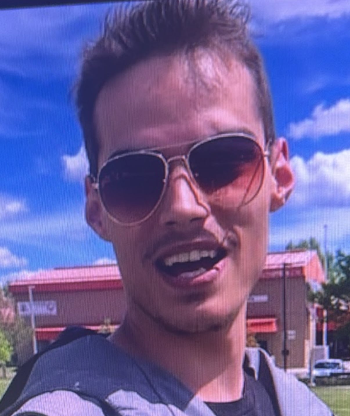 A man with short brown hair and sunglasses