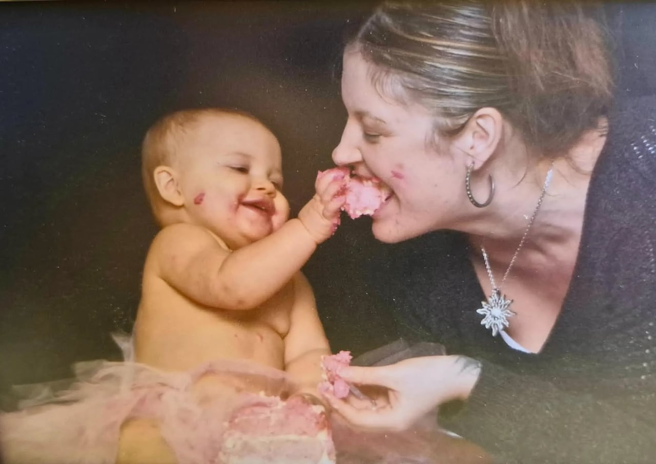 A woman eating cake out of a babies hand