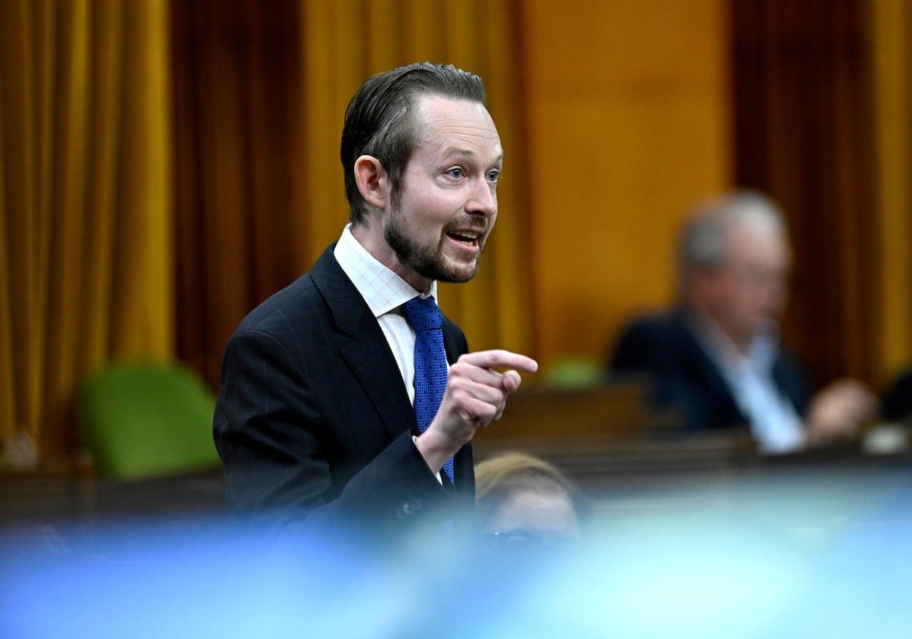 A man gestures in a legislative hall.