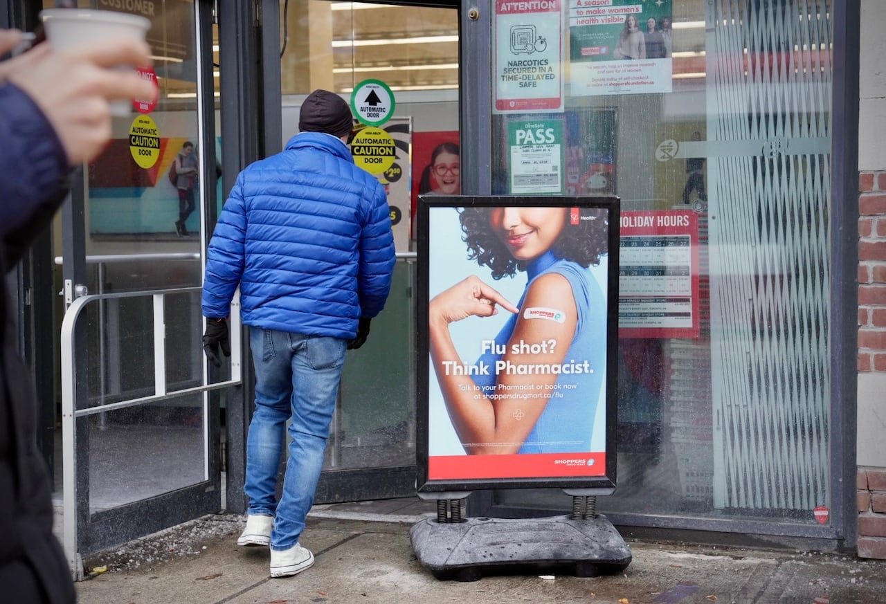Sign outside pharmacy urging people to get vaccinated as someone walks in to pharmacy