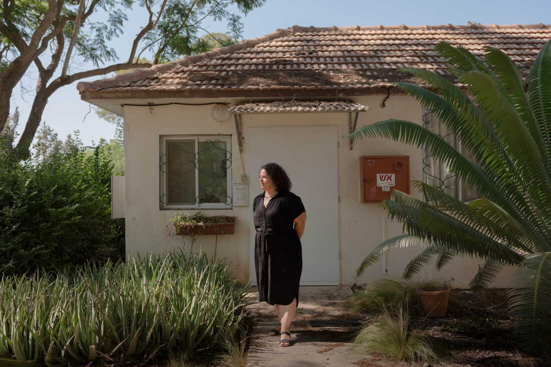 NIR OZ, ISRAEL, AUGUST 31, 2026: Galia Tzor, Nir Oz's recent resident from New Zealand, stands for a portrait outside of her office in the center of the kibbutz. Credit: Amit Elkayam for NPR.