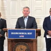 North Carolina Gov. Josh Stein, center, flanked by the state's health secretary, Dr. Dev Sangvai, left, and an executive from Undue Medical Debt, Jose Penabad, speaks about the elimination of medical debt through an initiative involving hospitals and Medicaid in Raleigh, N.C.