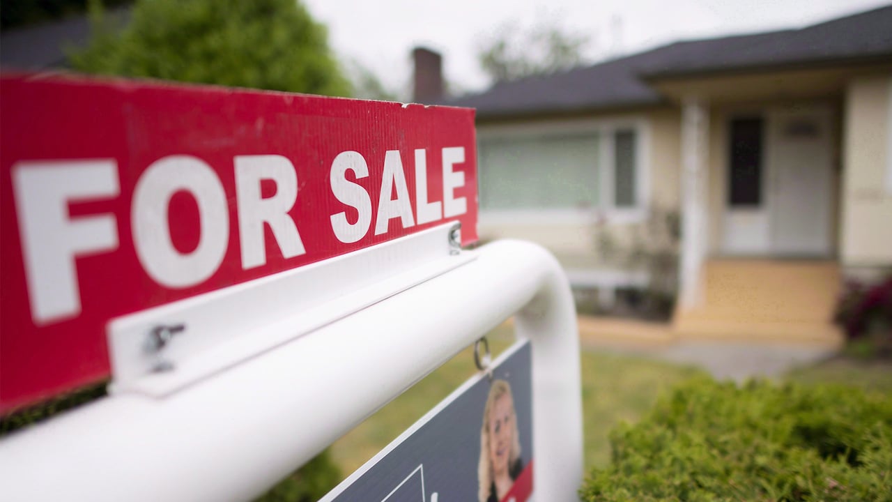 Close-up of a 'For sale' sign in front of a home.