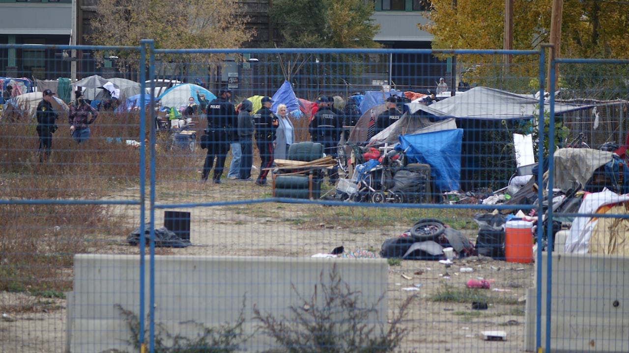 A fence with police and an encampment on the other side.