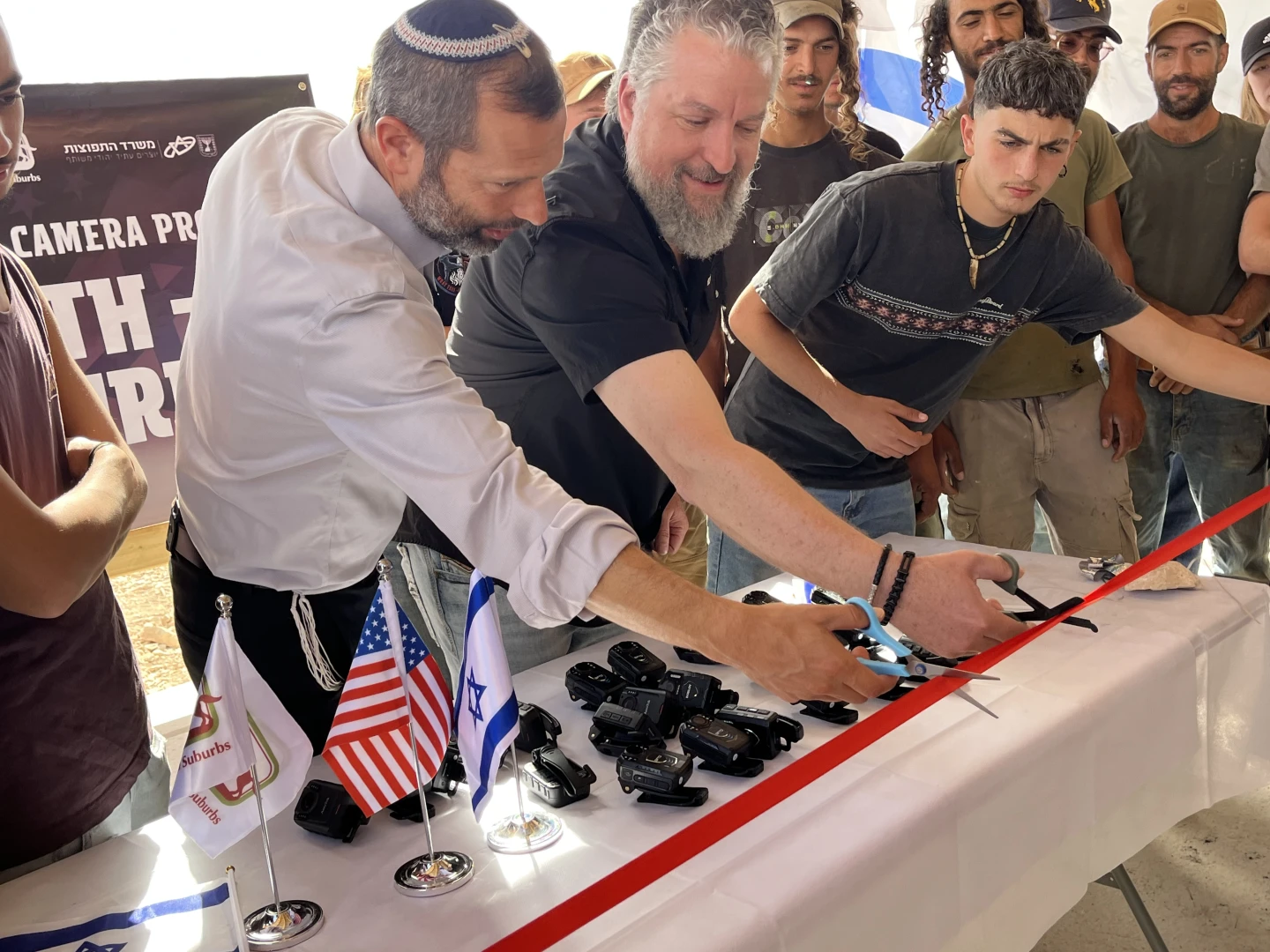 Binyamin Regional Council chairman Yisrael Ganz and Generation Zion founder Luke Moon cut the ribbon at the launch of the Shepherd Camera Project at the Ruach Ha’aretz agricultural farm in Binyamin, as local farmers and shepherds look on, Oct. 8, 2026. Photo by Josh Hasten.