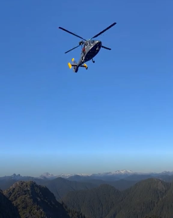 A helicopter in the sky far above a mountain range