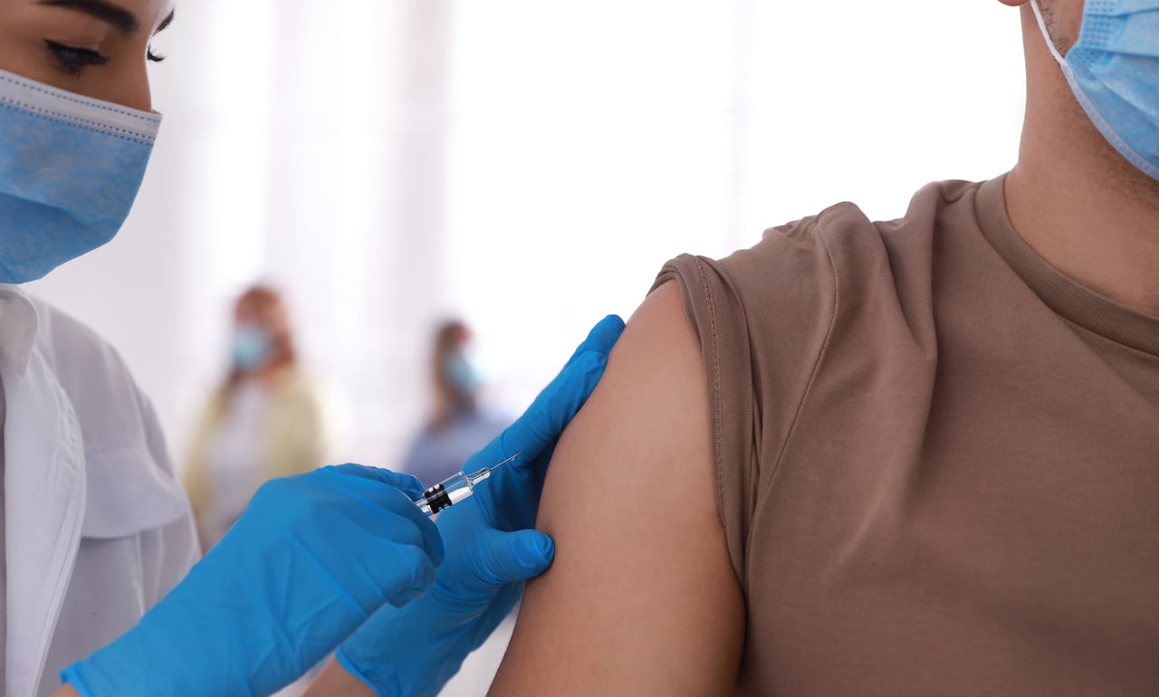 A doctor gives a shot to a patient in the arm.