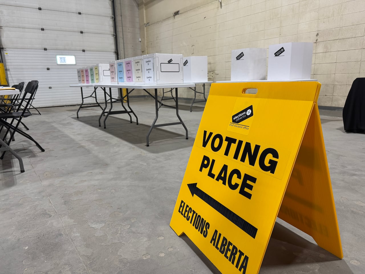 A yellow sign directing voters to a series of boxes lined along a table