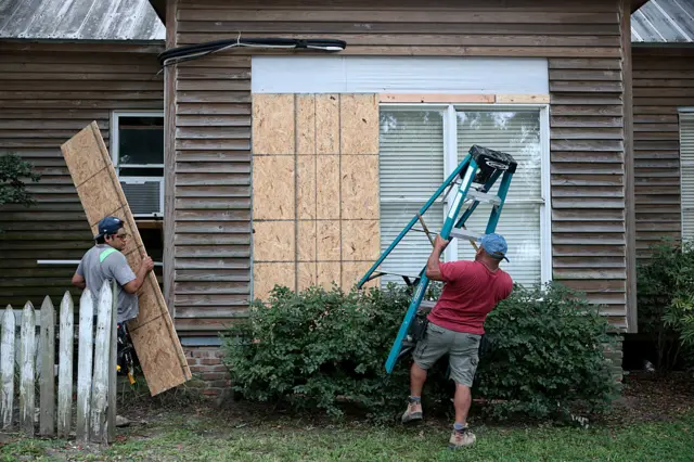 Residents in Pensacola board up the windows in front of their home