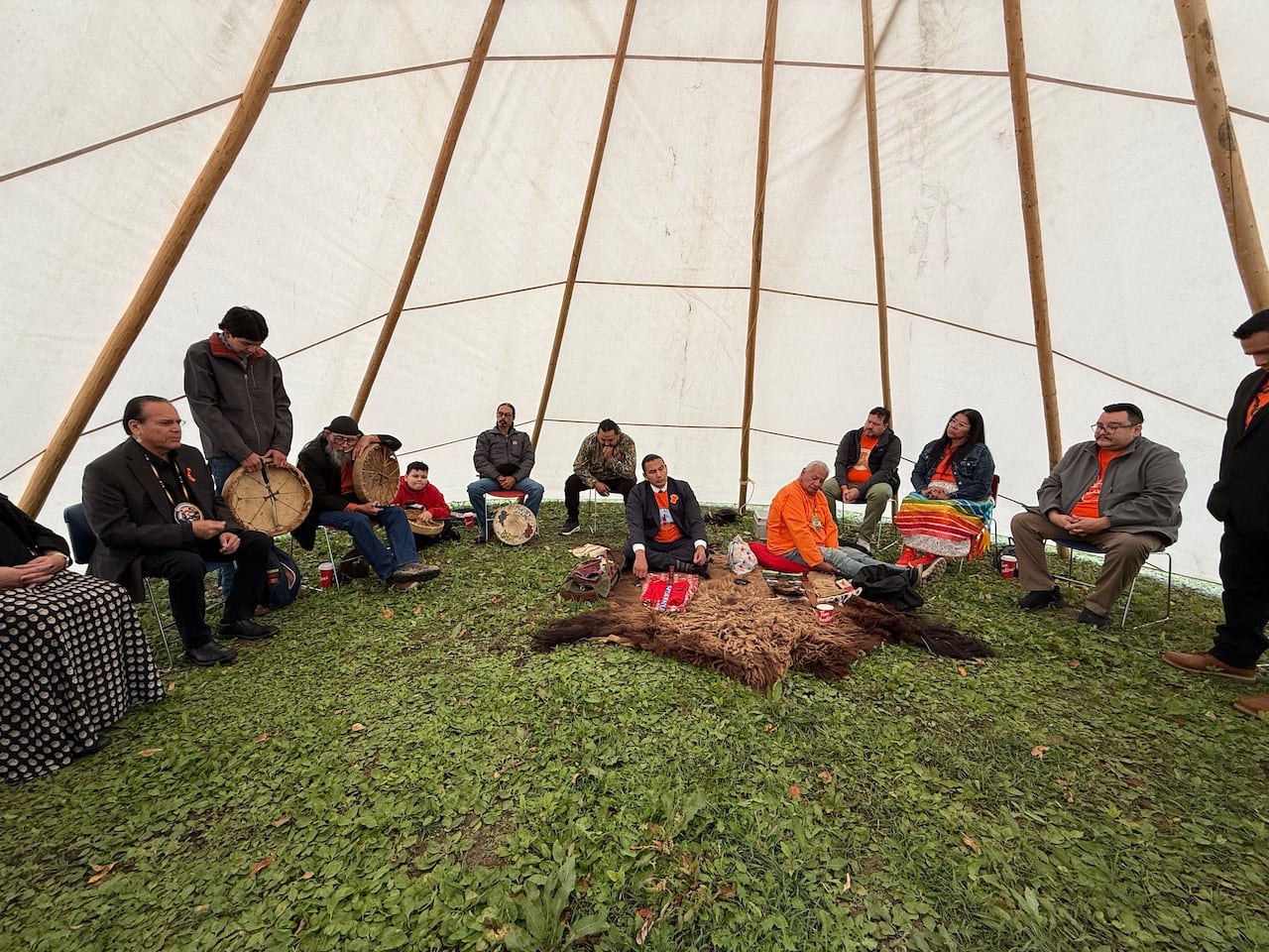 A group of people sit inside a teepee.