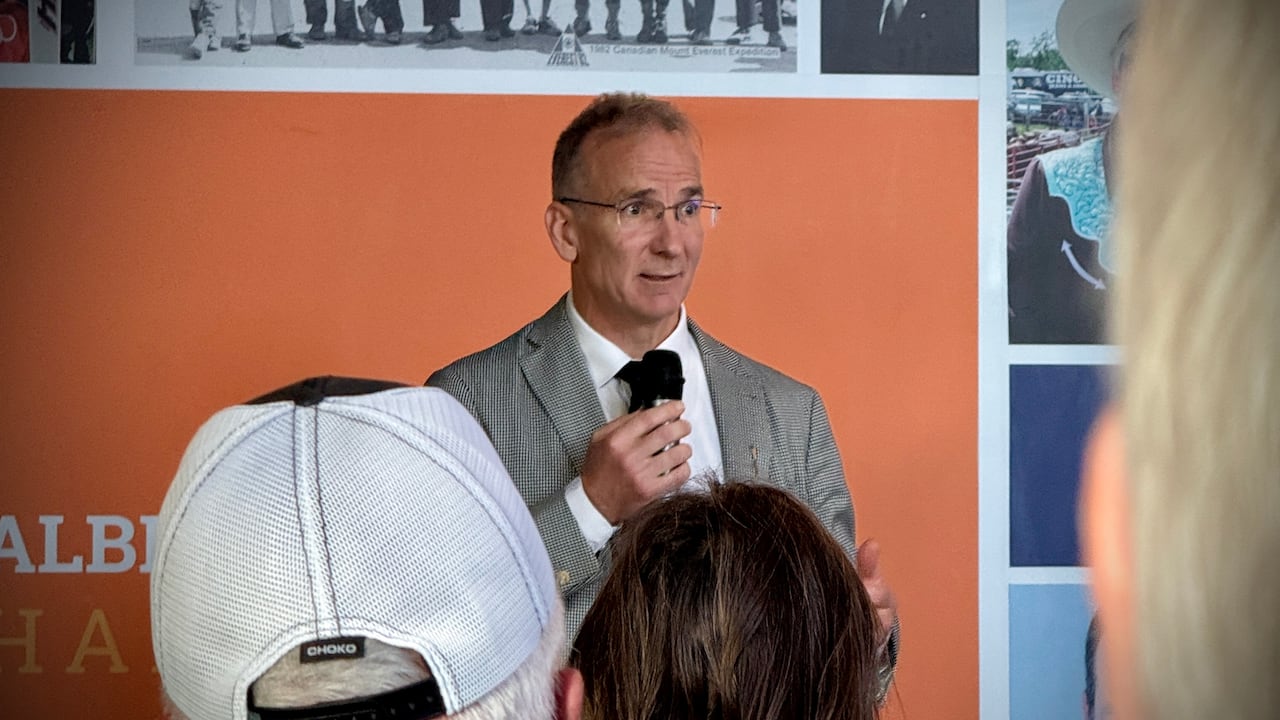 A man stands with a microphone talking to a crowd.