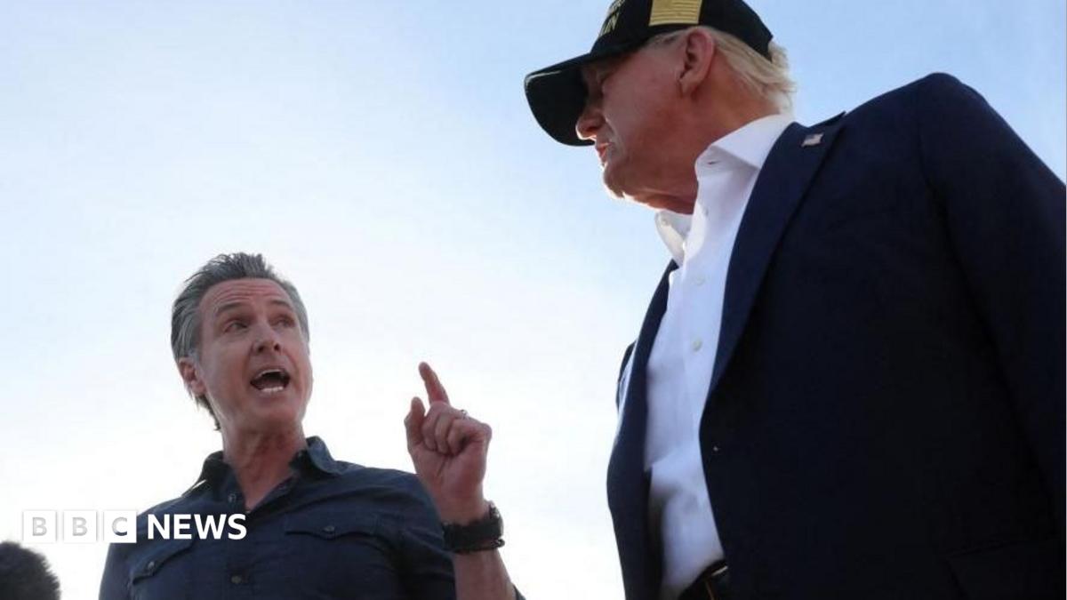 California Governor Gavin Newsom and US President Donald Trump shake hands on airport tarmac. Trump, on the right, wears a baseball cap.