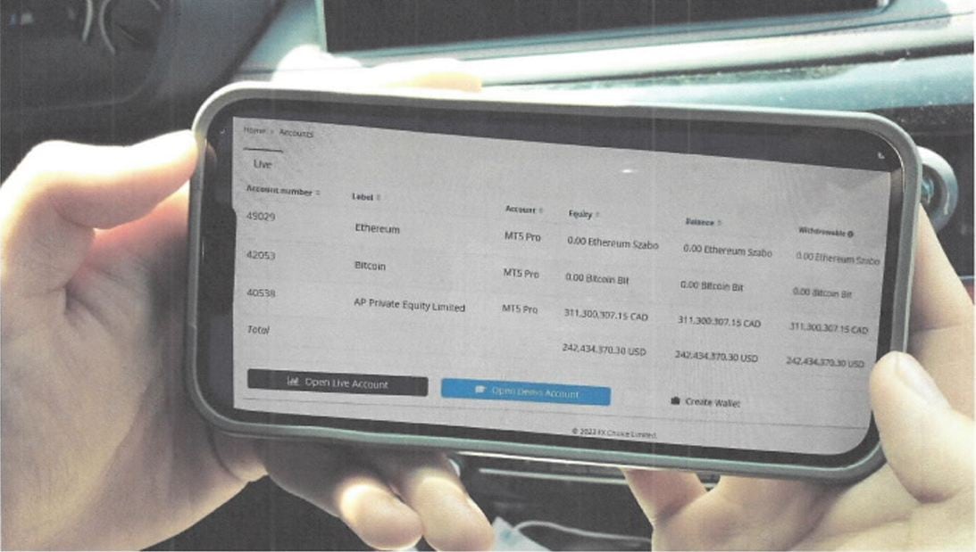 Someone holding a phone with trading account information on the screen.