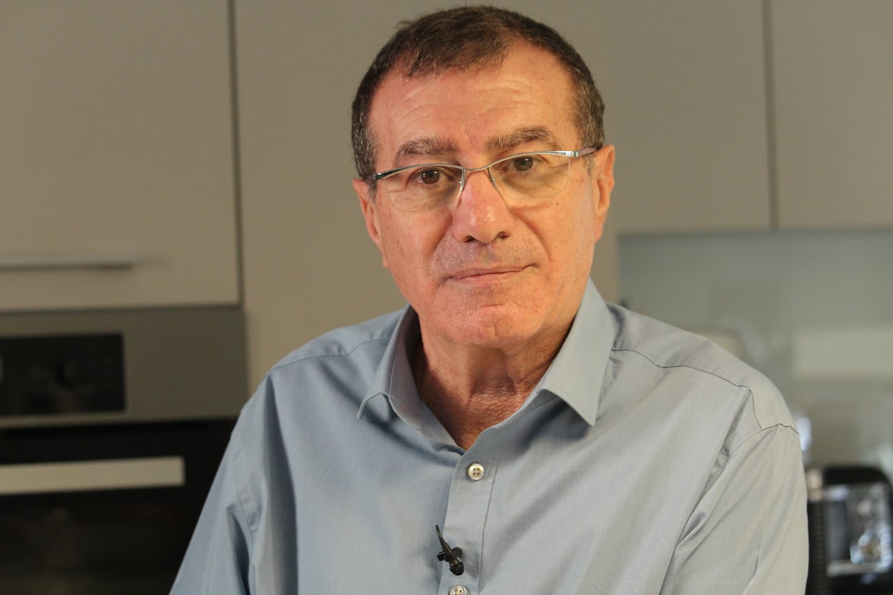 A man wearing a dress shirt and glasses poses for a photo.