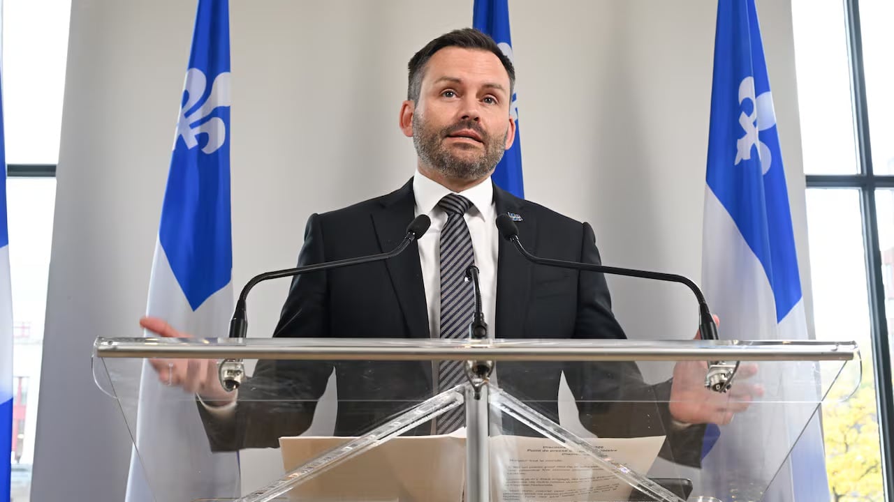 Paul St-Pierre Plamondon speaks at a podium with two Quebec flags behind him.